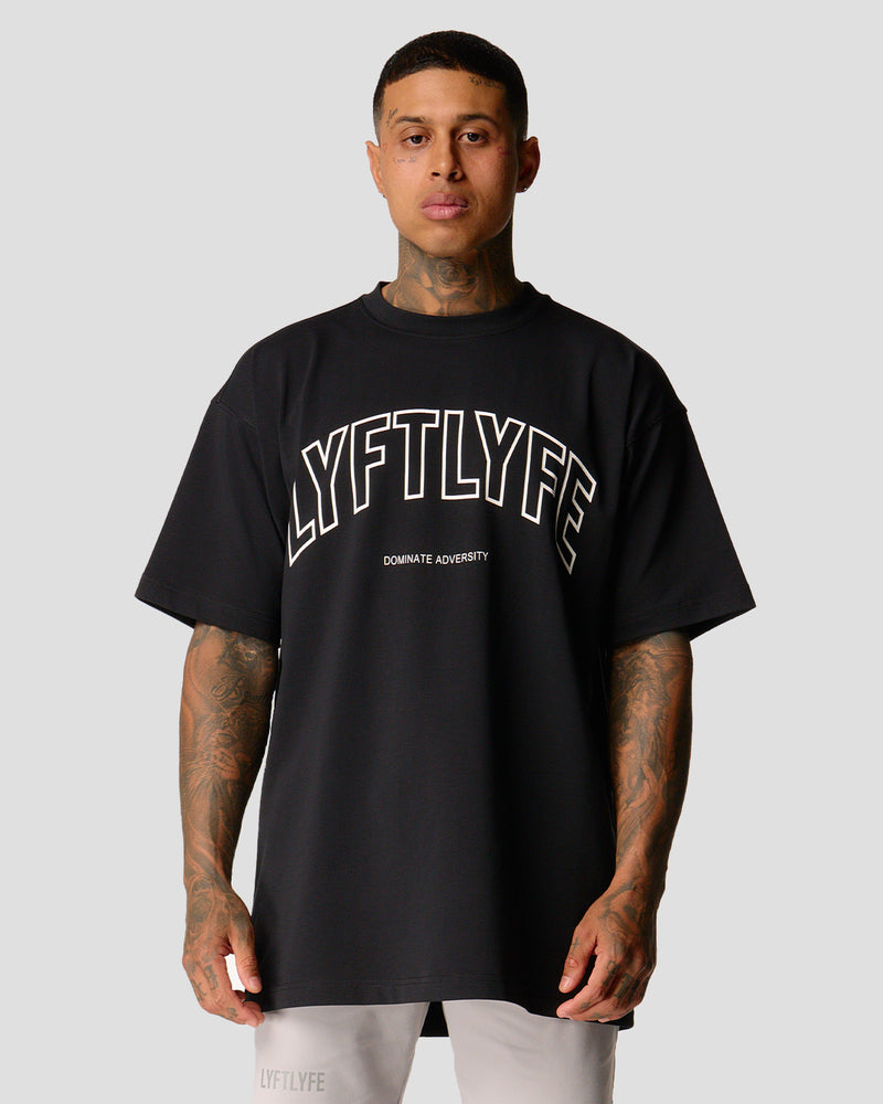 A male athlete is in a black oversized T-shirt with a large lyftlyfe logo on the chest.