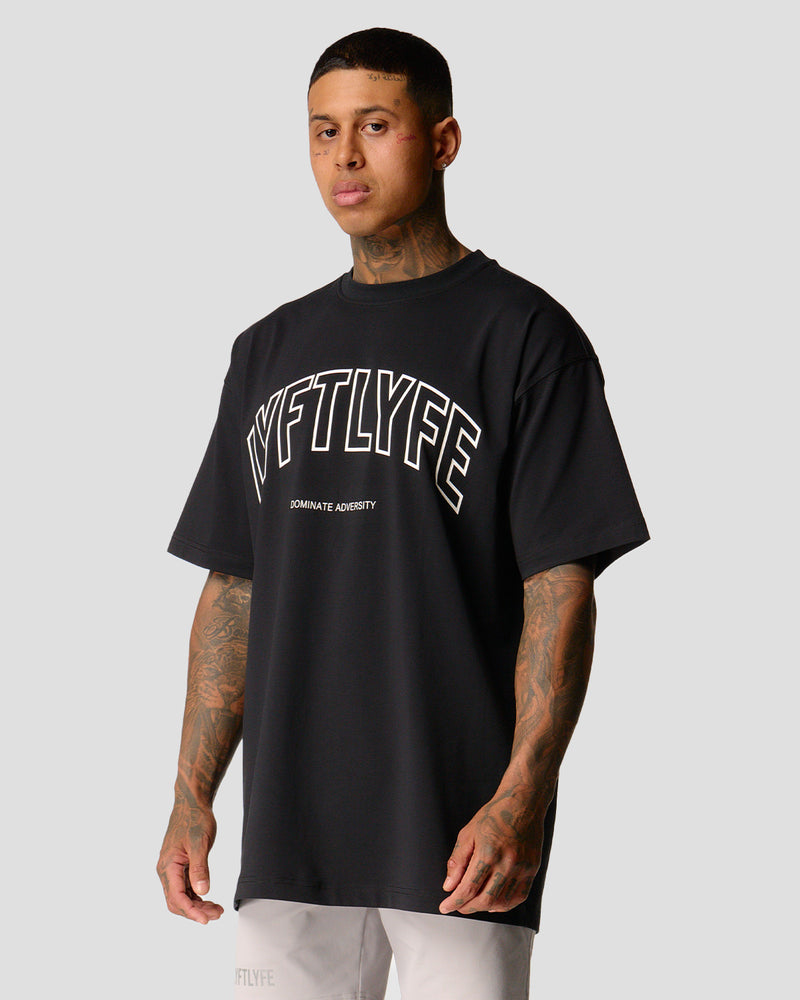 A male athlete is in a black oversized T-shirt with a large lyftlyfe logo on the chest.