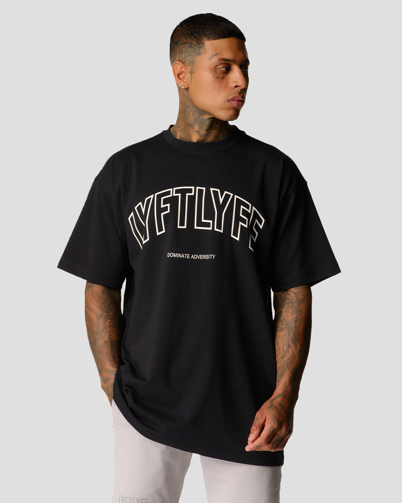 A male athlete is in a black oversized T-shirt with a large lyftlyfe logo on the chest.