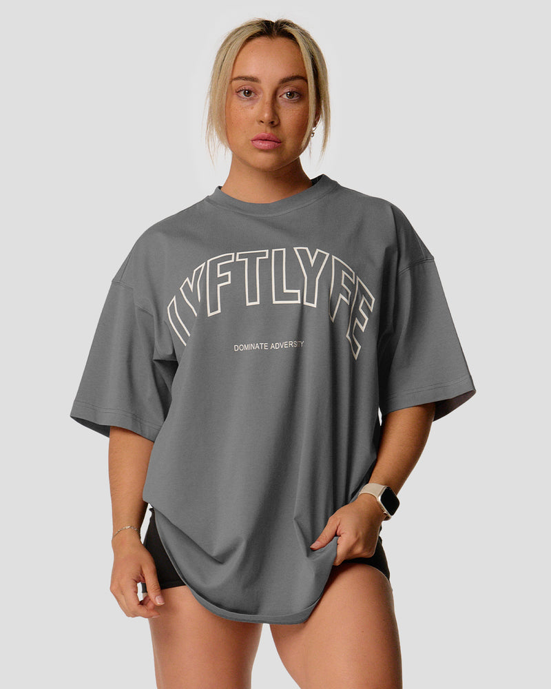 A female athlete is in a gray oversized T-shirt with a large lyftlyfe logo on the chest.