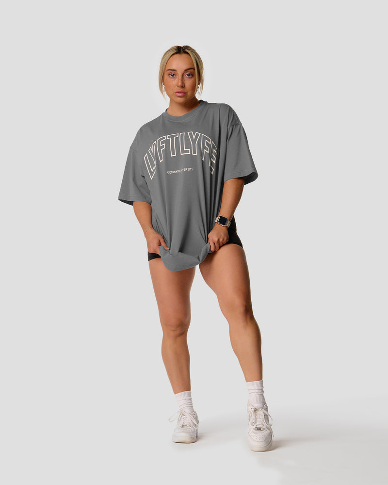 A female athlete is in a gray oversized T-shirt with a large lyftlyfe logo on the chest.