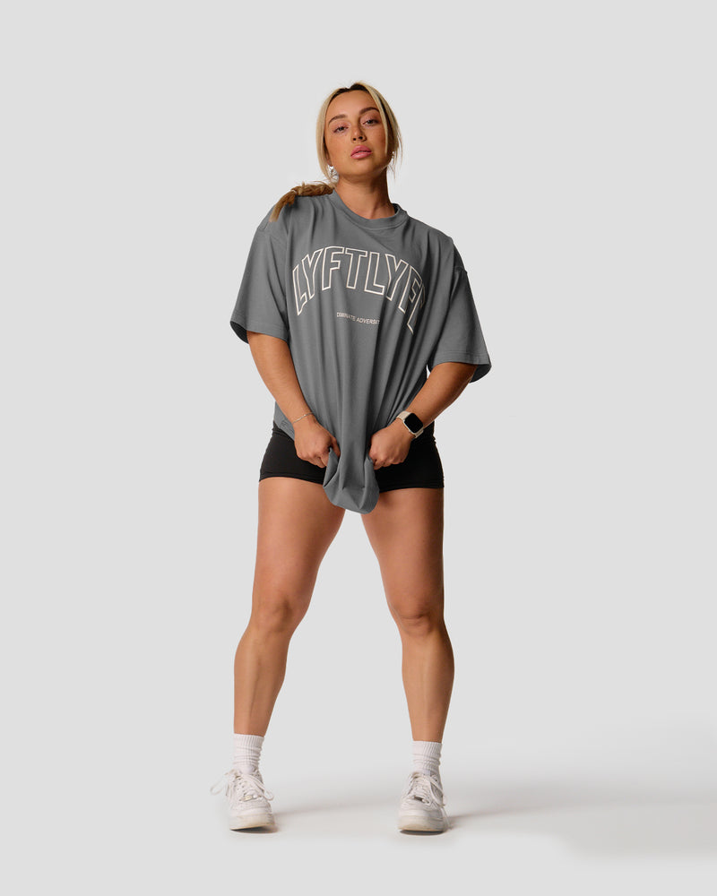 A female athlete is in a gray oversized T-shirt with a large lyftlyfe logo on the chest.