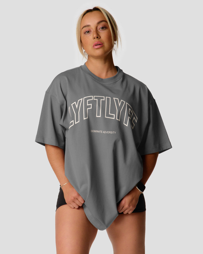 A female athlete is in a gray oversized T-shirt with a large lyftlyfe logo on the chest.