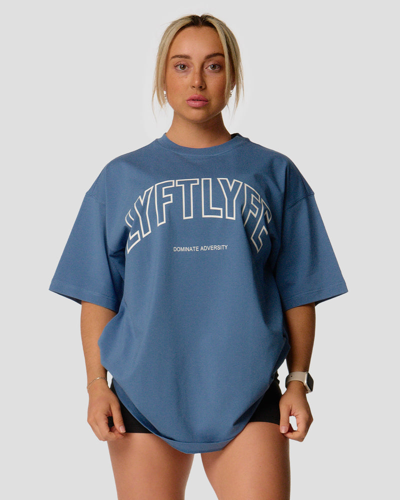 A female athlete is wearing a blue, oversized T-shirt featuring a large lyftlyfe logo across the chest.