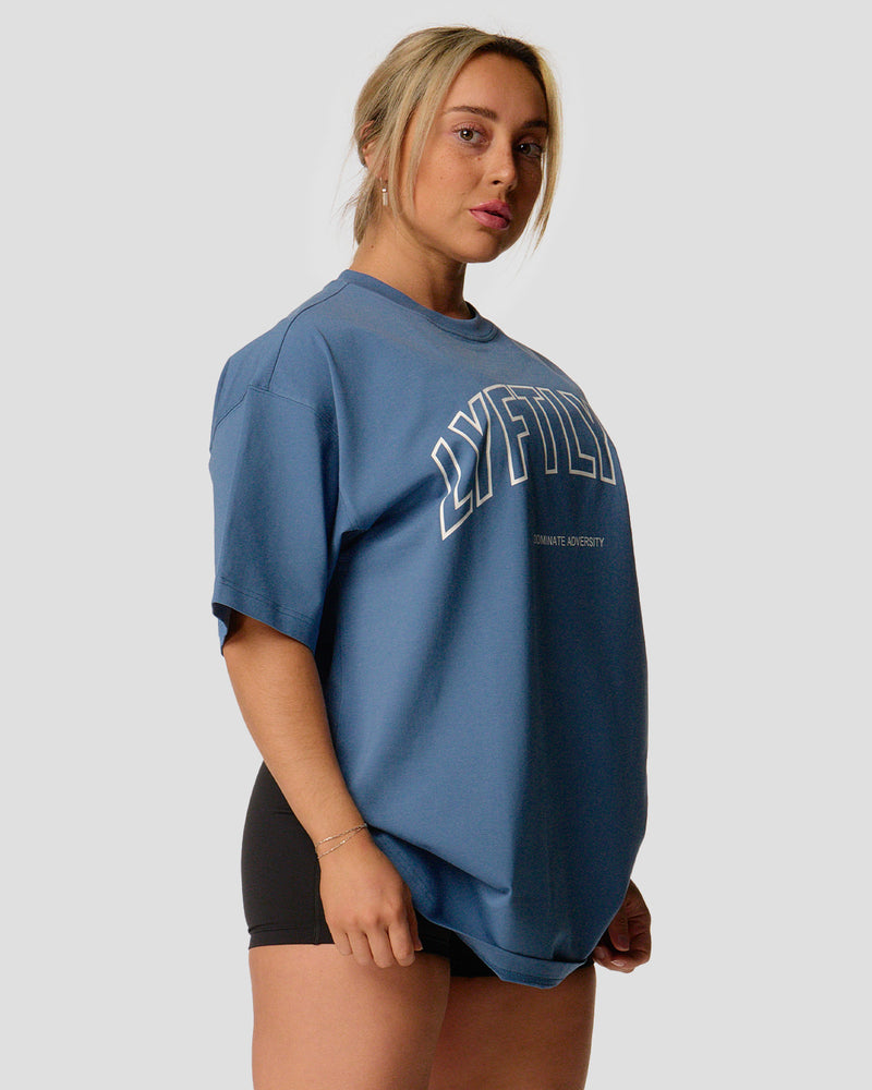 A female athlete is wearing a blue, oversized T-shirt featuring a large lyftlyfe logo across the chest.