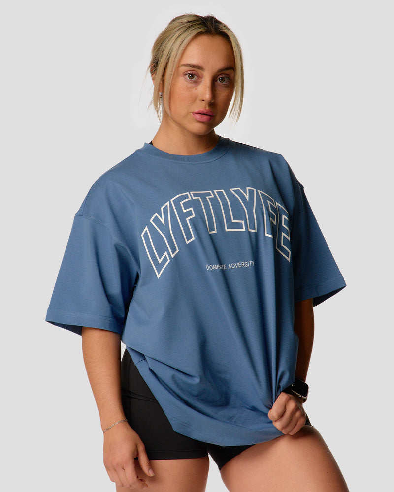 A female athlete is wearing a blue, oversized T-shirt featuring a large lyftlyfe logo across the chest.