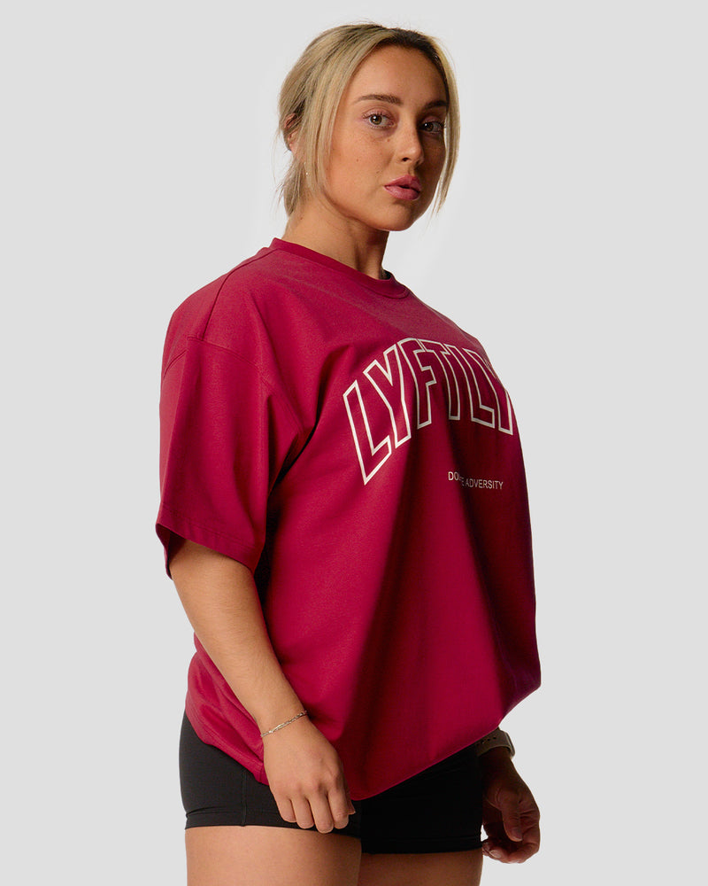 A female athlete is wearing a red, oversized T-shirt featuring a large lyftlyfe logo across the chest.