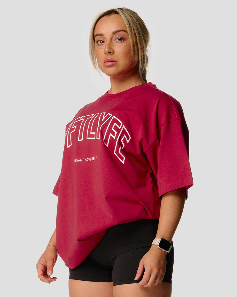 A female athlete is wearing a red, oversized T-shirt featuring a large lyftlyfe logo across the chest.