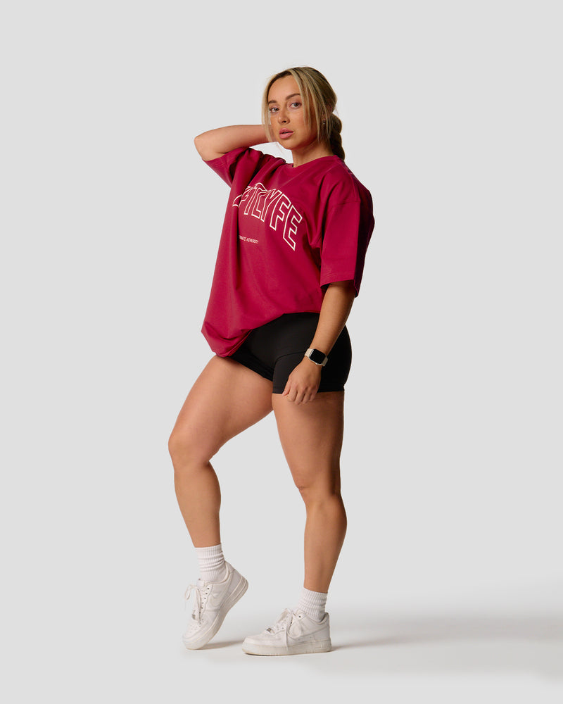 A female athlete is wearing a red, oversized T-shirt featuring a large lyftlyfe logo across the chest.