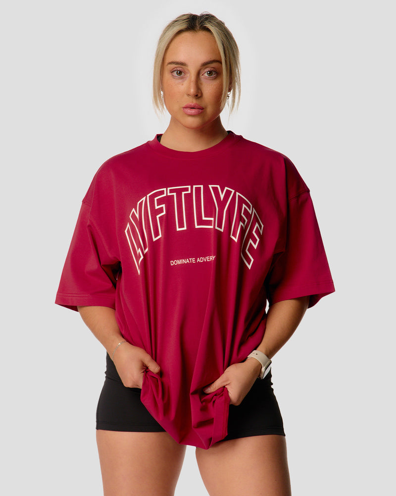 A female athlete is wearing a red, oversized T-shirt featuring a large lyftlyfe logo across the chest.