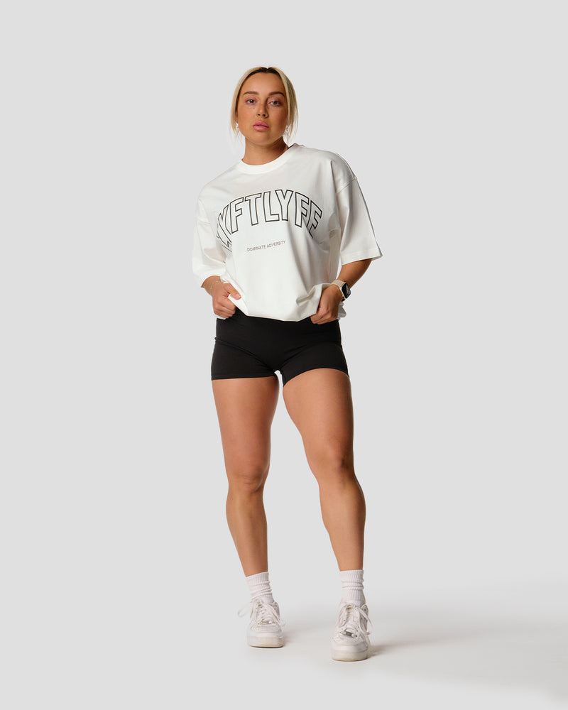 A female athlete is in a white oversized T-shirt with a large lyftlyfe logo on the chest.