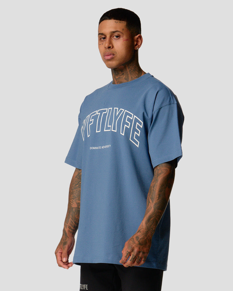 A male athlete is in a blue oversized T-shirt with a large lyftlyfe logo on the chest.