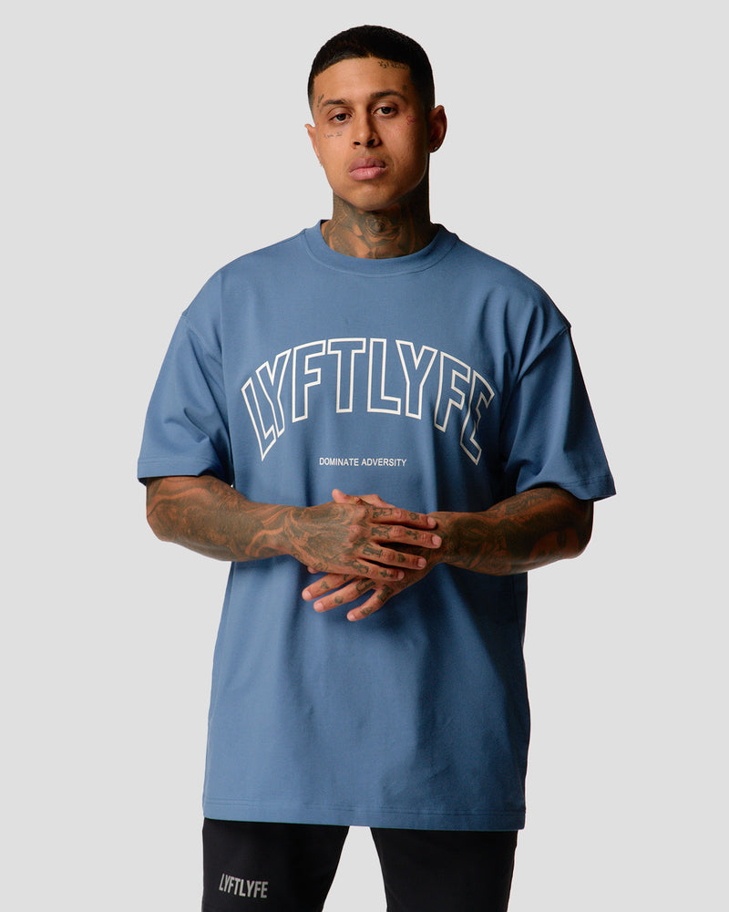 A male athlete is in a blue oversized T-shirt with a large lyftlyfe logo on the chest.