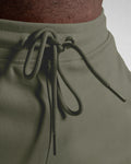 Zoomed view of green shorts waistband with tonal drawstrings and metal tips.