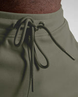 Zoomed view of green shorts waistband with tonal drawstrings and metal tips.