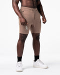 Men’s workout shorts in taupe viewed from the left side, featuring clean stitch lines and deep pockets.