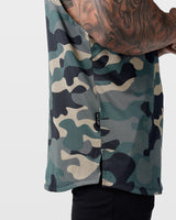 Close-up of Dominate Adversity side tag on Limitless Cut Sleeve hem in green camo.