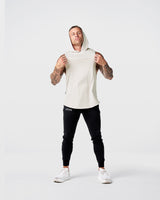 Front view of Limitless Men’s Sleeveless Hoodie in off-white with hood, split hem, and reflective chest logo.