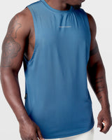 Close-up of reflective Dominate Adversity logo on chest of Limitless Cut Sleeve tank in dark blue.