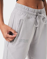 Detailed shot of the invisible pocket with tonal zipper on women’s light grey joggers for secure storage.