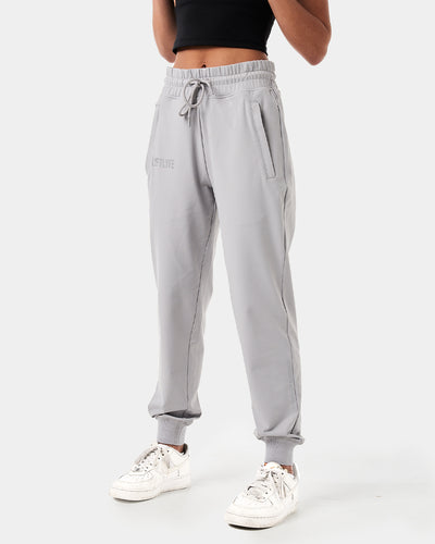 Women’s light grey joggers designed for style and performance with reflective branding and sleek, streamlined fit.