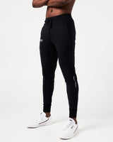 Side view of men’s Breathe Joggers in black featuring the slogan 'Dominate Adversity' on the lower left leg and secure zippered pockets.