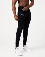 Men’s black performance joggers with a reflective logo, side view highlighting sweat-wicking fabric, tonal drawstring, and cuffed hem.