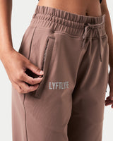 Detailed shot of the invisible pocket with tonal zipper on women’s brown joggers for secure storage.