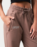 Detailed view of the ergonomic pocket placement on brown women’s joggers with premium lightweight fabric.