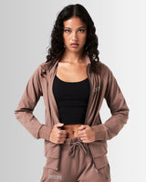 Front profile of women’s high-performance zip-up jacket in brown, crafted from moisture-wicking, lightweight fabric for mobility.