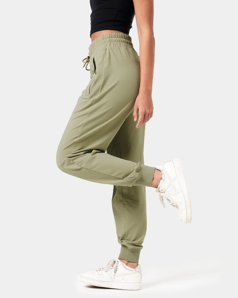 Close-up of the 'Dominate Adversity' slogan printed on the lower leg of women’s green Breathe Joggers, showcasing attention to detail.