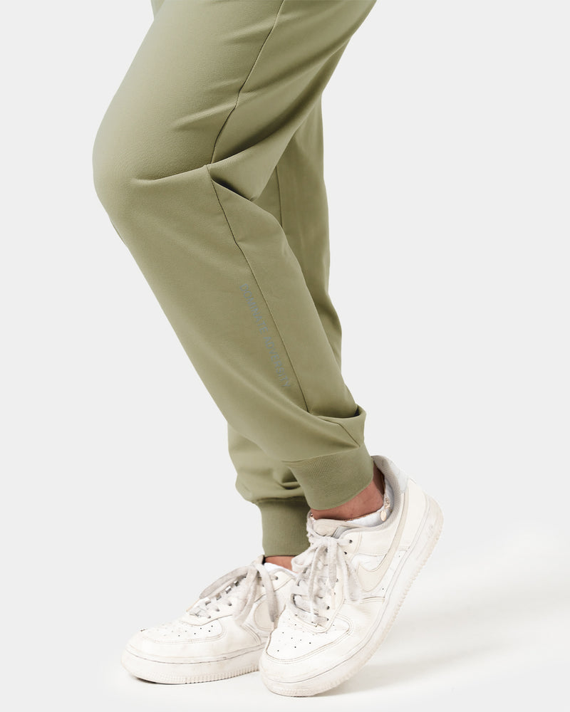 Close-up of the 'Dominate Adversity' slogan printed on the lower leg of women’s green Breathe Joggers, showcasing attention to detail.
