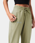 Detailed shot of the invisible pocket with tonal zipper on women’s  green joggers for secure storage.