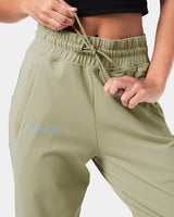 Close-up of the reflective Lyftlyfe logo on the right thigh of women’s green Breathe Joggers with a thick waistband.