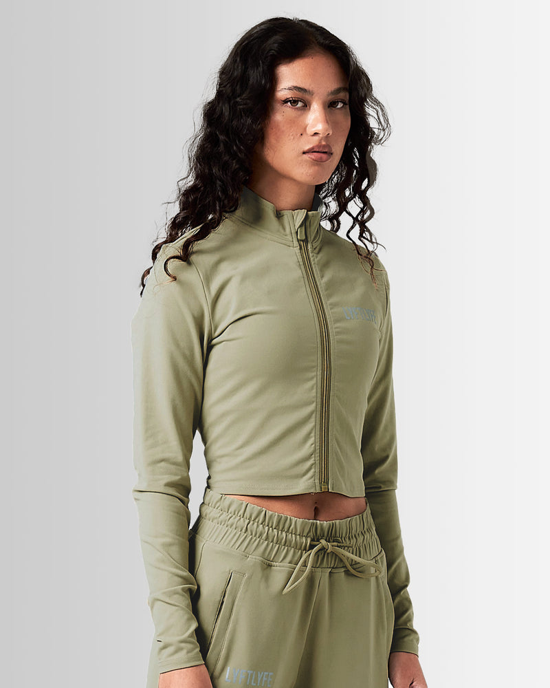 Front view of Breathe Women’s Zip-Up Crop in green with a reflective Lyftlyfe logo on the left chest and a flattering cropped fit.