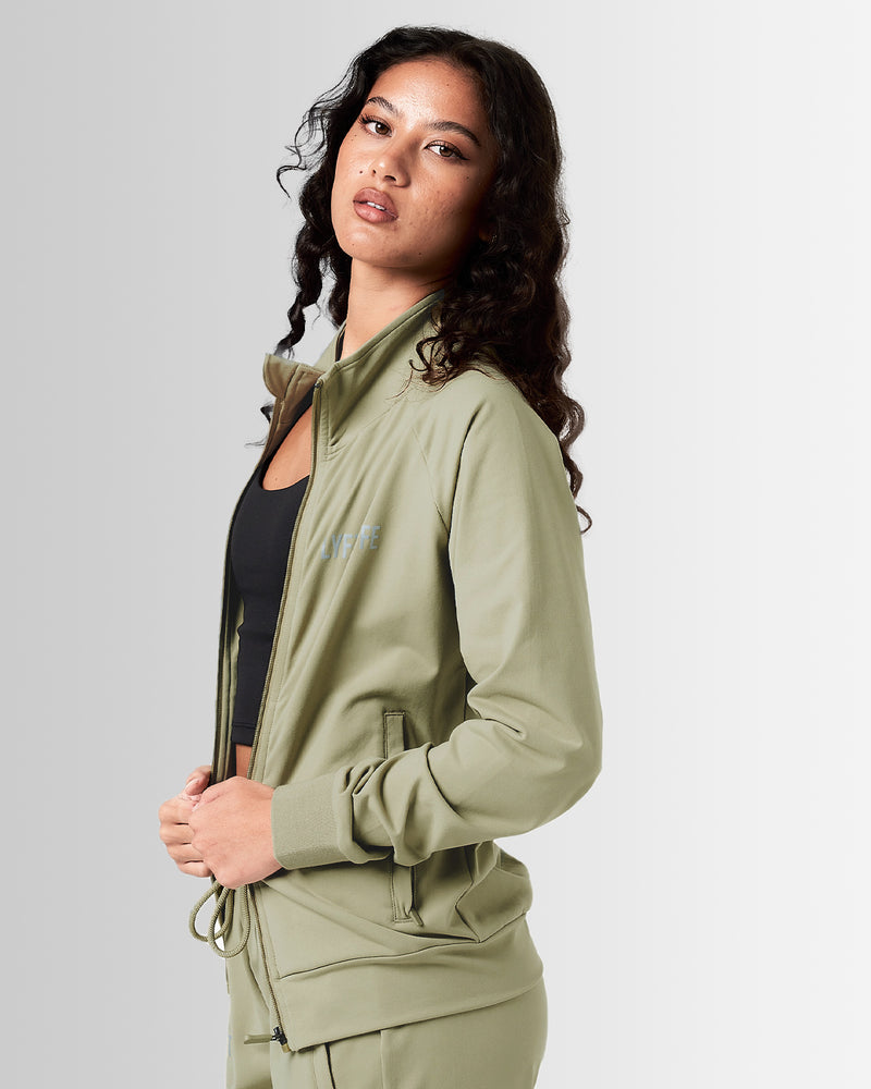 Women’s green Breathe Zip-Up Jacket featuring a minimalist reflective Lyftlyfe logo on the left chest and a streamlined, athletic fit.