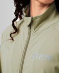 Close-up of the custom zipper closure and head cover on women’s Breathe Zip-Up Jacket in green, highlighting premium stitching and technical design.