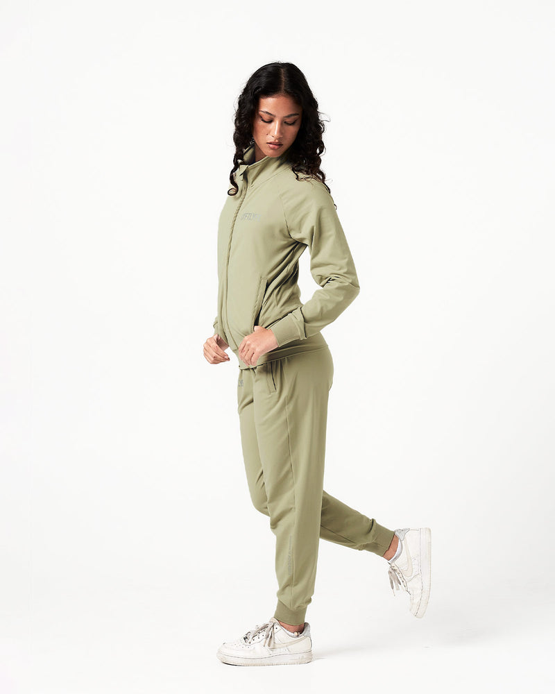 Side angle of women’s breathable joggers in green with reflective slogan and sleek tonal stitching.