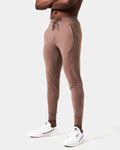Left Side view of men’s Breathe Joggers in brown featuring the slogan 'Dominate Adversity' on the lower left leg and secure zippered pockets.