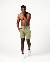 Men’s lightweight performance shorts in green with secure invisible pockets, wide waistband, and reflective branding.