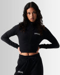 Front view of Breathe Women’s Zip-Up Crop in black with a reflective Lyftlyfe logo on the left chest and a flattering cropped fit.