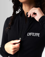 Close-up of the custom zipper closure on the Breathe Women’s Zip-Up Crop in black, featuring a sleek head cover and tonal stitching.