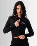 Black cropped performance jacket for women, highlighting reflective branding, shaping fit, and premium breathable fabric.