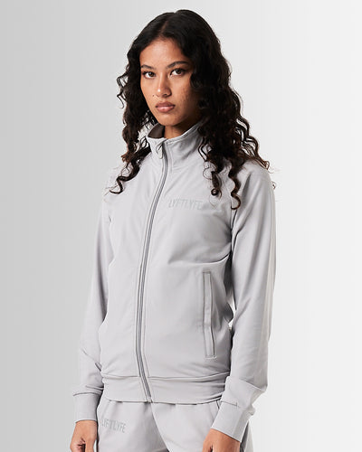 Women’s Breathe Zip-Up Jacket in light grey, designed for performance with a sleek fit and reflective branding.