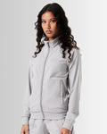 Women’s light grey performance zip-up jacket, side profile showcasing breathable material and functional locking zipper pockets.