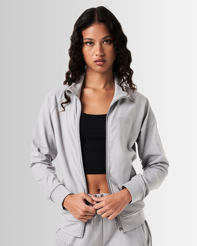 Women’s Breathe Zip-Up Jacket in light grey, designed for performance with a sleek fit and reflective branding.