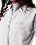 Close-up of the custom zipper closure and head cover on women’s Breathe Zip-Up Jacket in light grey, highlighting premium stitching and technical design.