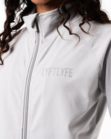 Close-up of the custom zipper closure and head cover on women’s Breathe Zip-Up Jacket in light grey, highlighting premium stitching and technical design.