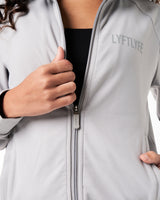 Detailed view of the zipper design on women’s streamlined zip-up jacket in light grey.