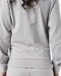 Detailed back view of women’s light grey Breathe Jacket highlighting the reflective 'Dominate Adversity' branding on the lower back.